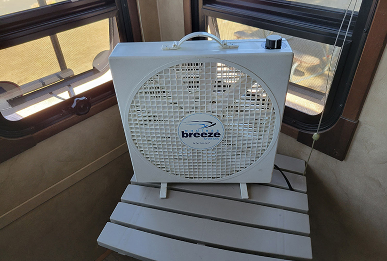 the Endless Breeze fan set up on a table next to the windows of an RV
