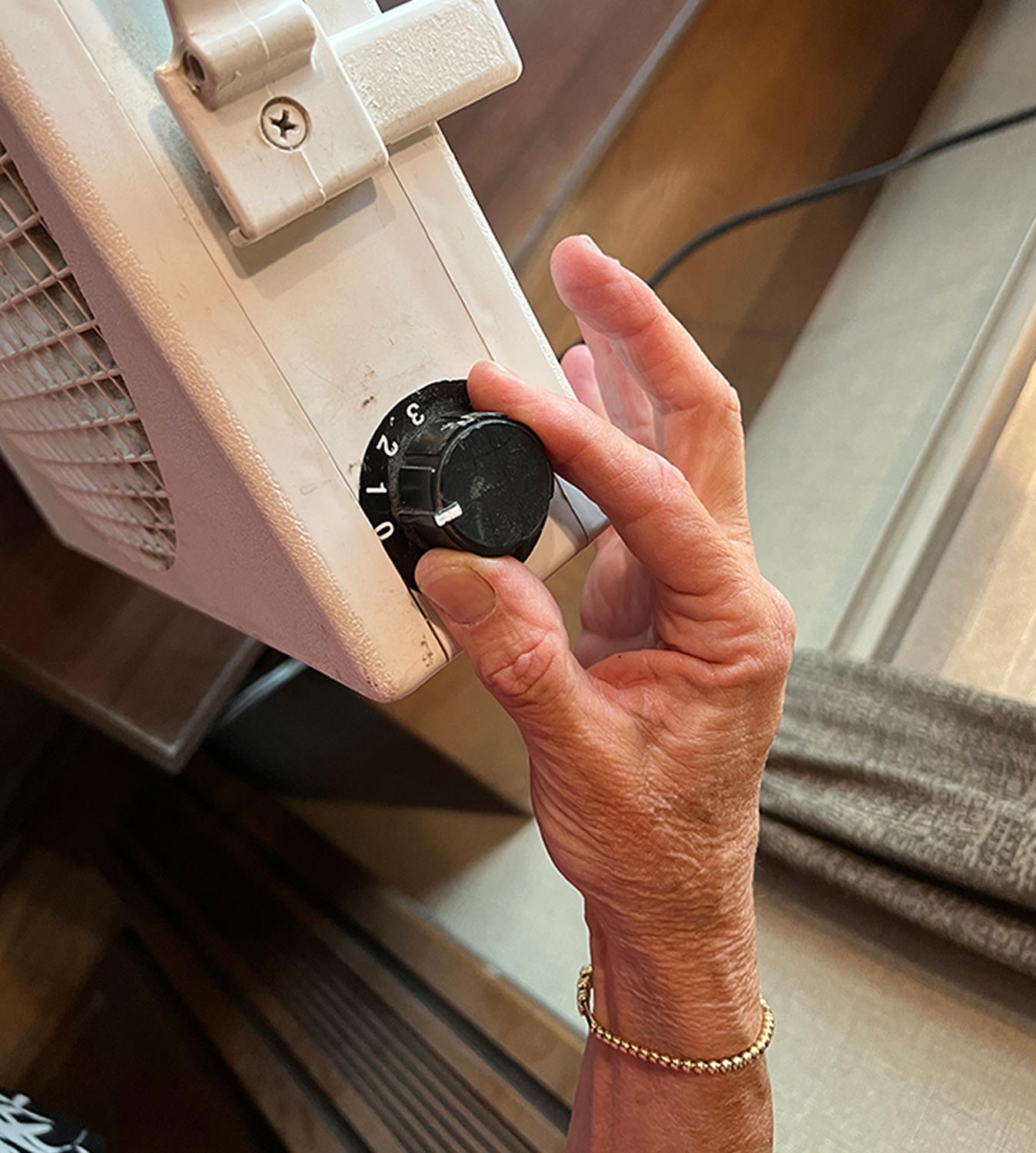 a hand turns the three speed dial on the side of the Endless Breeze fan