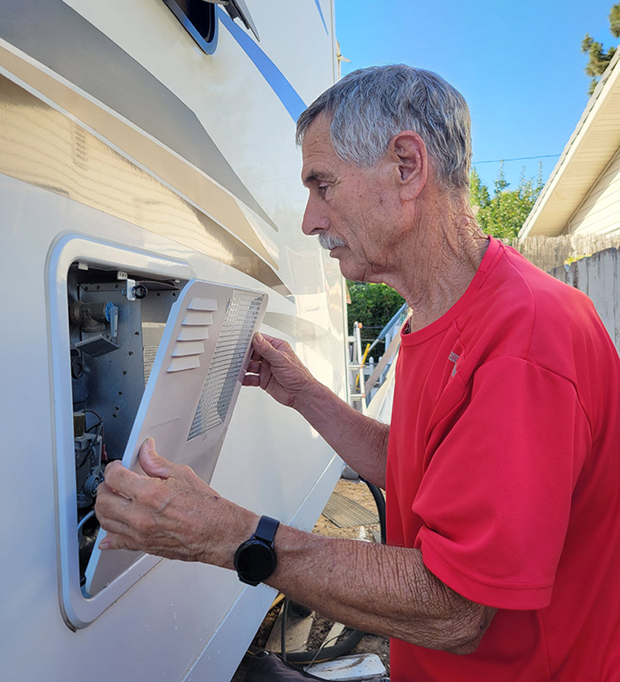 man working on AC unit outside an RV