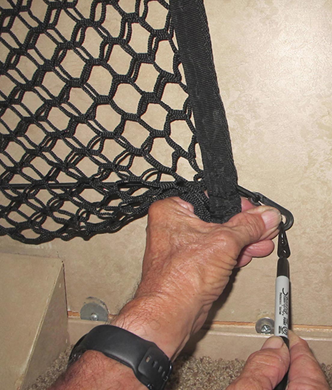 technician uses a sharpie to mark the position of the bottom right hook on the wall