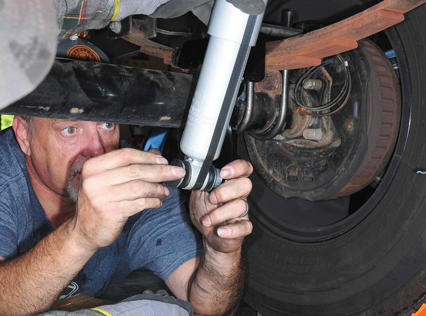 the mechanic snugs a nut on the attached lower shock