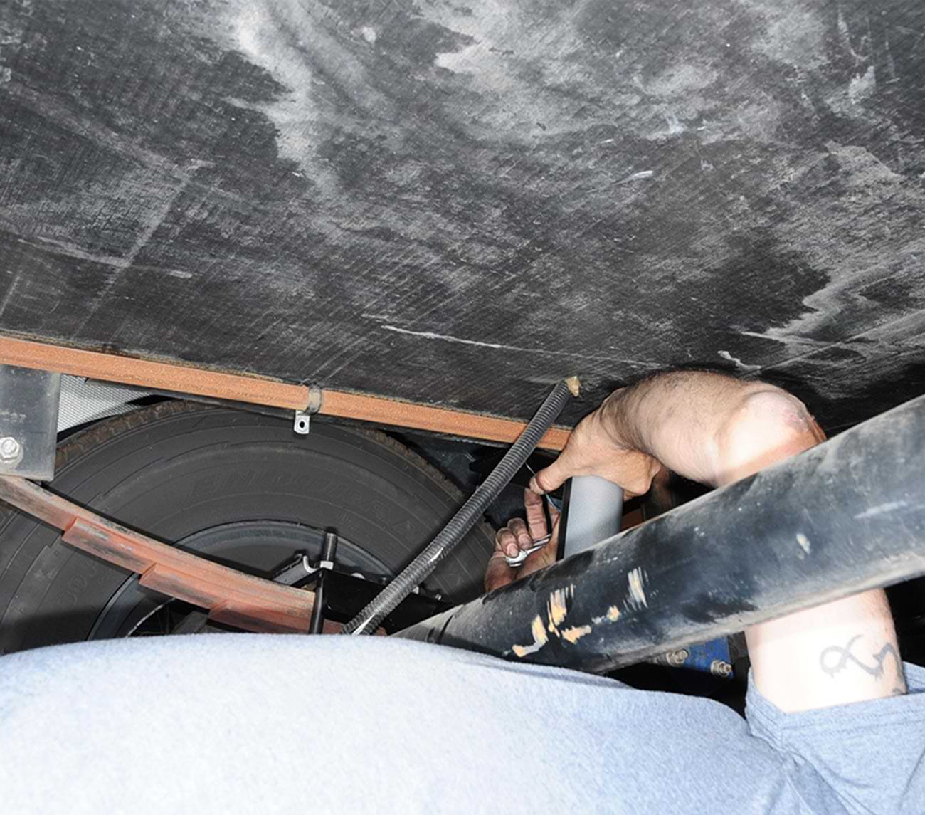 mechanic lays under the RV while relocating the LP-gas pipe