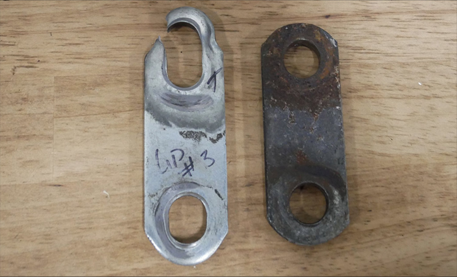 top view of an elongated bolt hole and a rusted bolt hole sitting on a table