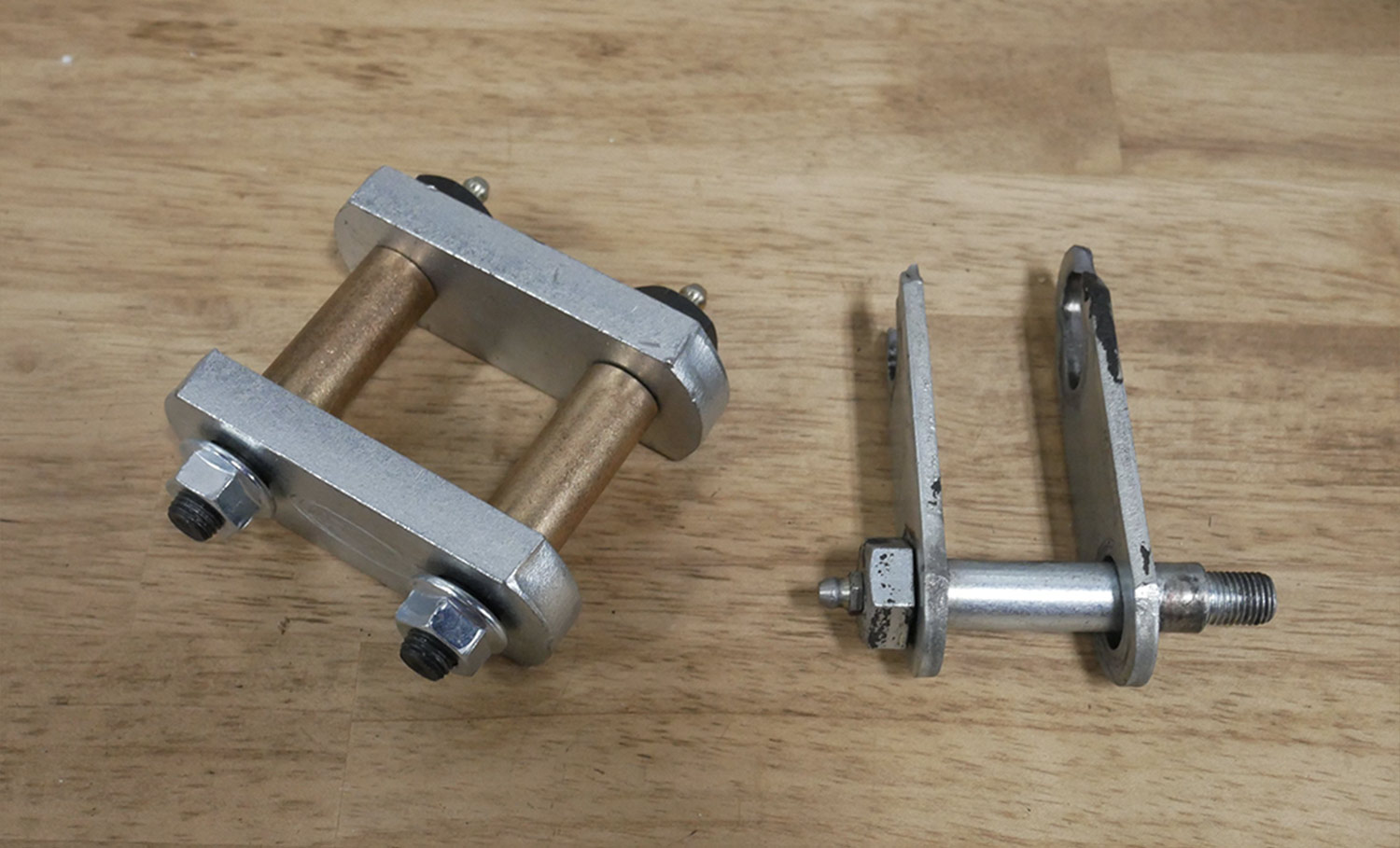 top view of two worn stock shackle brackets sitting on a table