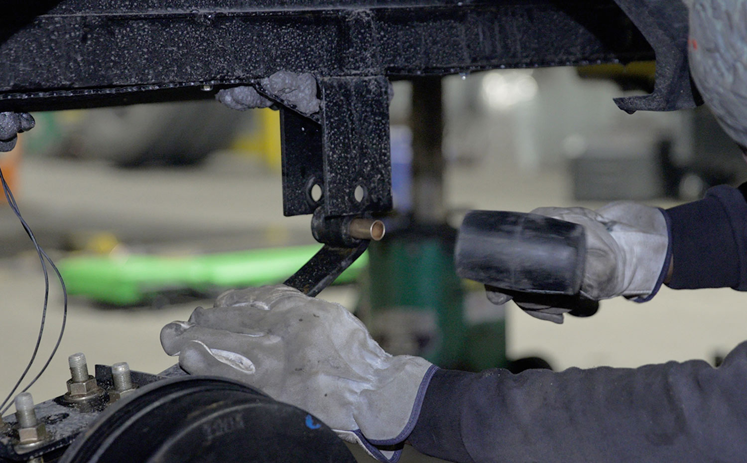 RV mechanic uses a rubber mallet to punch out the stock plastic bushing from inside the leaf spring eyes