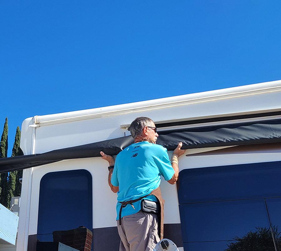 man installing a new window awning on his RV