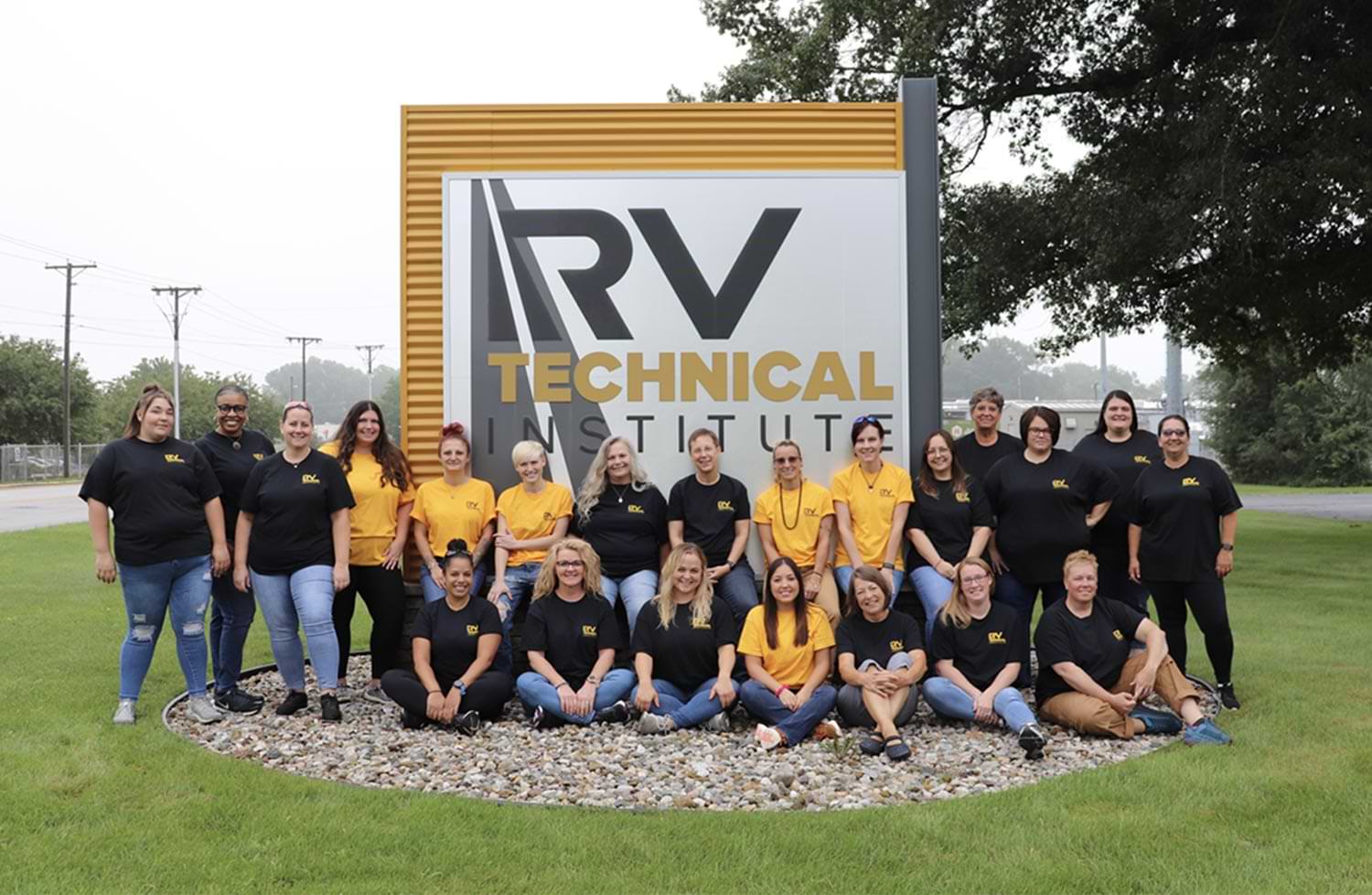 members of the RV Women's Alliance stand for a large group photo in front of the RV Technical Institute sign