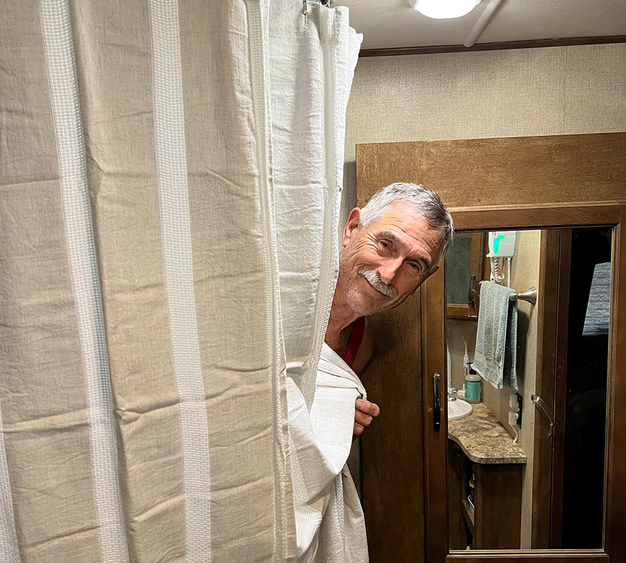 man sticking his head out behind a shower curtain