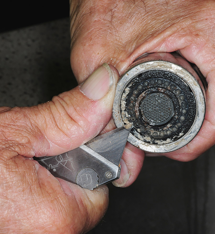 Bigger chunks of stubborn calcium were removed from the metal ring with a razor knife. They came off easily, but care must be taken to prevent cutting the plastic spray nozzles, which were then cleaned individually with a safety pin.