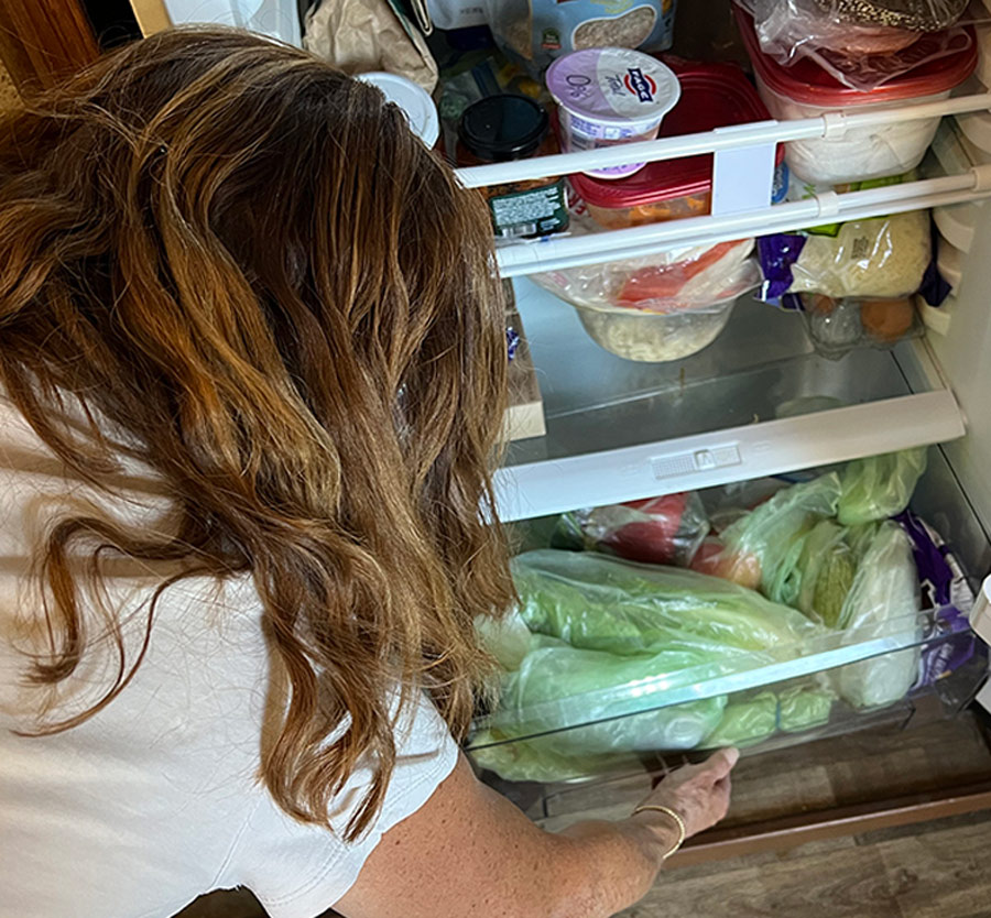 woman opening the bottom drawer of a fridge