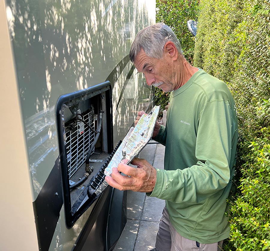 man looking at vent cover outside of RV