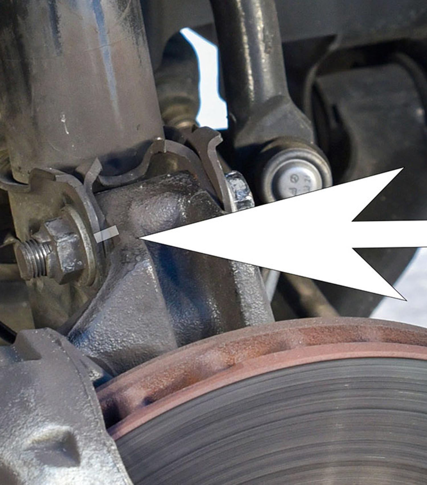 a graphic line and white arrow mark the position of the strut’s mounting bracket in relation to the steering knuckle