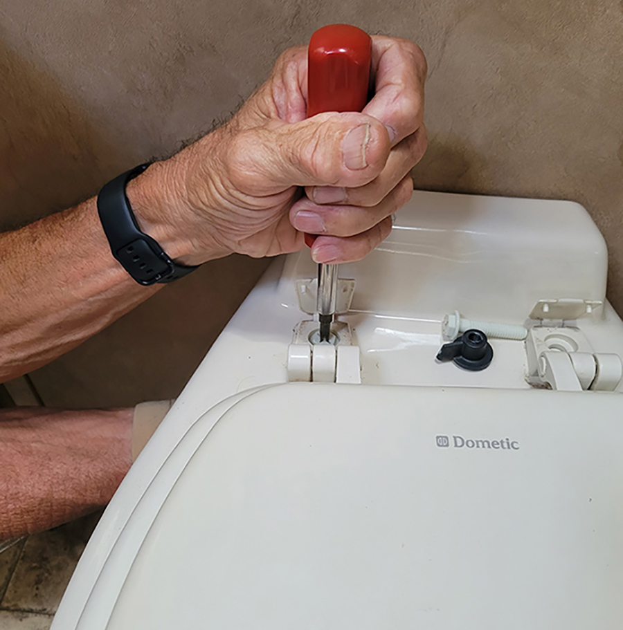 Someone unscrewing a toilet seat form a toilet