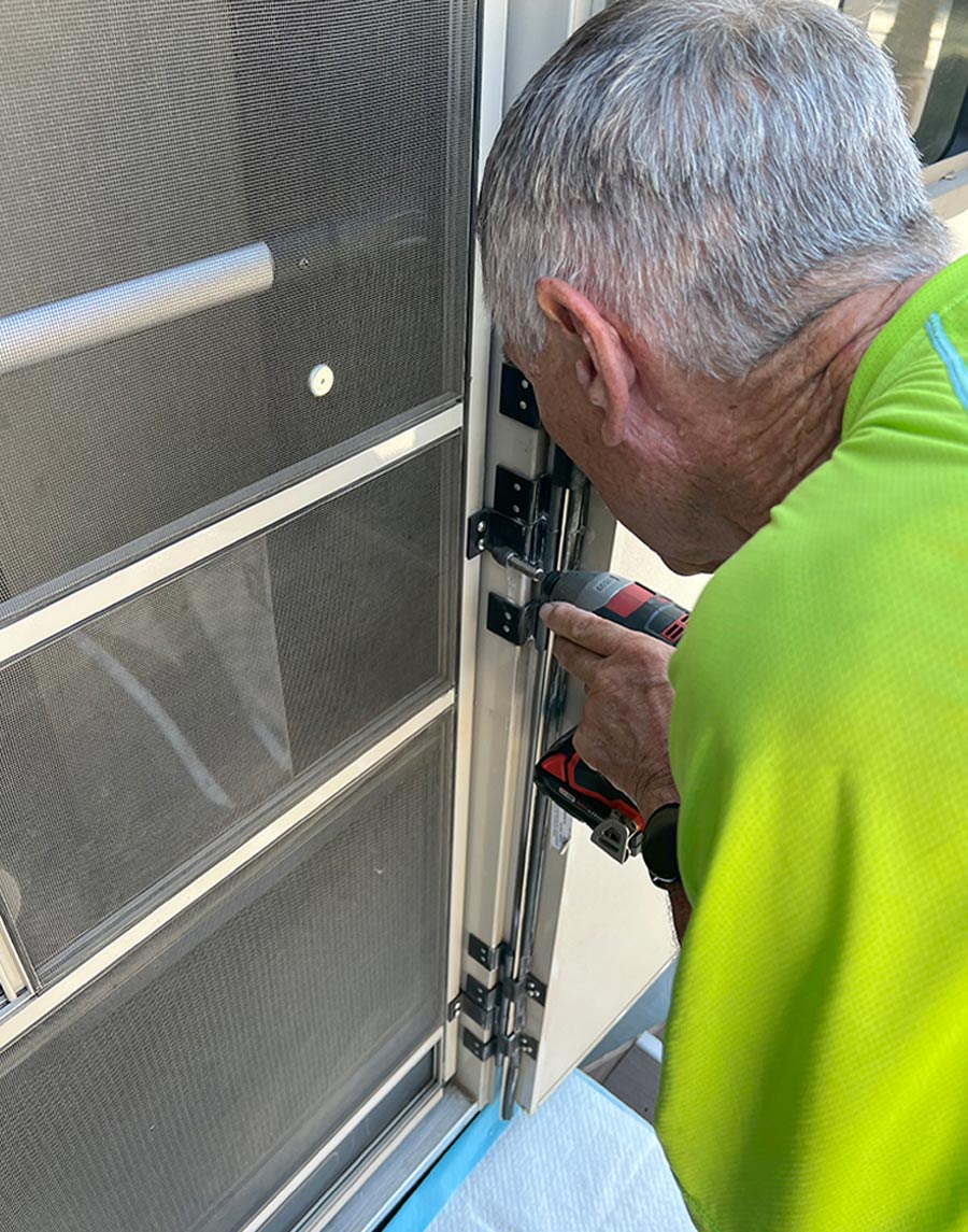 man screwing hinge onto screen door