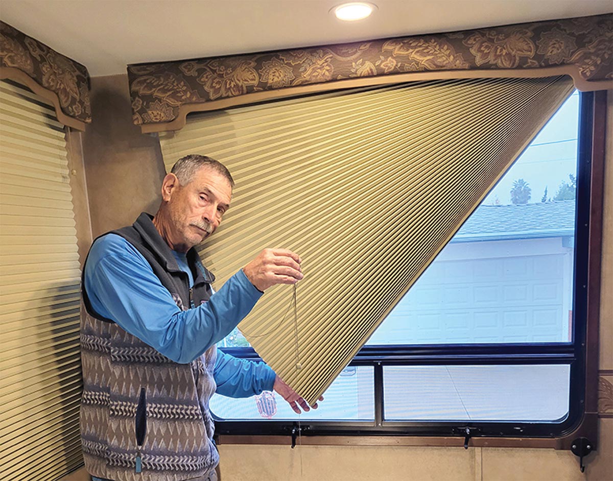 Bill Gehr holding broken window blind strings in RV