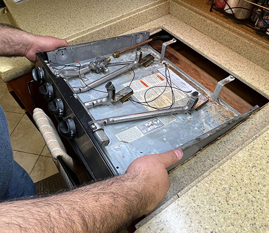 After the gas line is sealed off, then the four wood screws that hold the stove to the counter are removed. Once the mounting screws are removed the old cooktop can be easily lifted out and sent to the RV scrapyard.