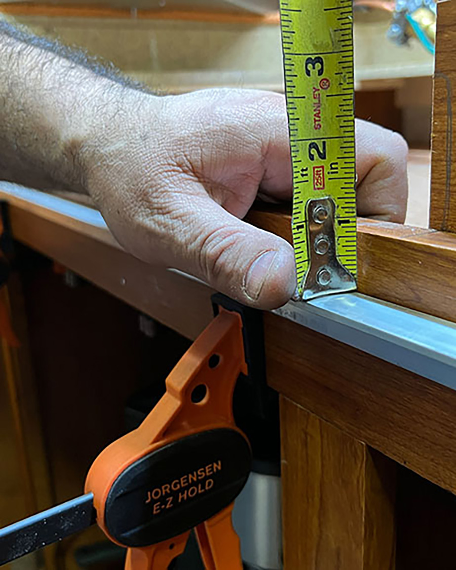 Salazar cut a 24-inch-long length of aluminum — the same width as the replacement cooktop — and clamped it in place to act as a trim guide to give a straight cut across the facia when using his reciprocating multi-tool.