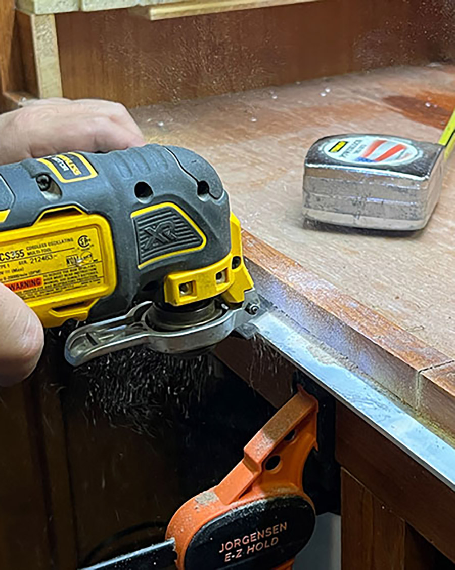 A reciprocating multi-tool makes short work of cutting the facia and Corian countertop so the new cooktop will drop into place. This install required making four small notches, two on each side, to allow clearance for the Suburban’s side mounting protrusion to clear the factory countertop cutout.