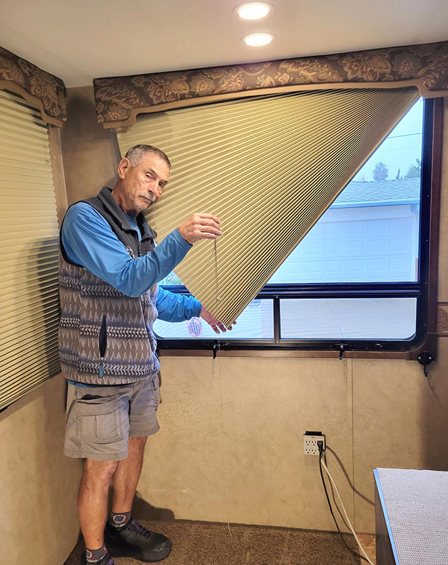 man standing next to window blinds where only one side is pulled up