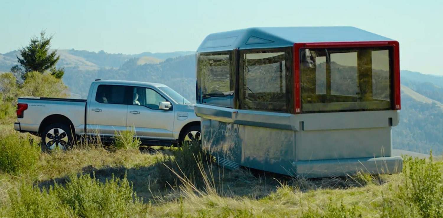 three quarter view of the Lightship trailer stationed atop a hill near a parked pickup truck