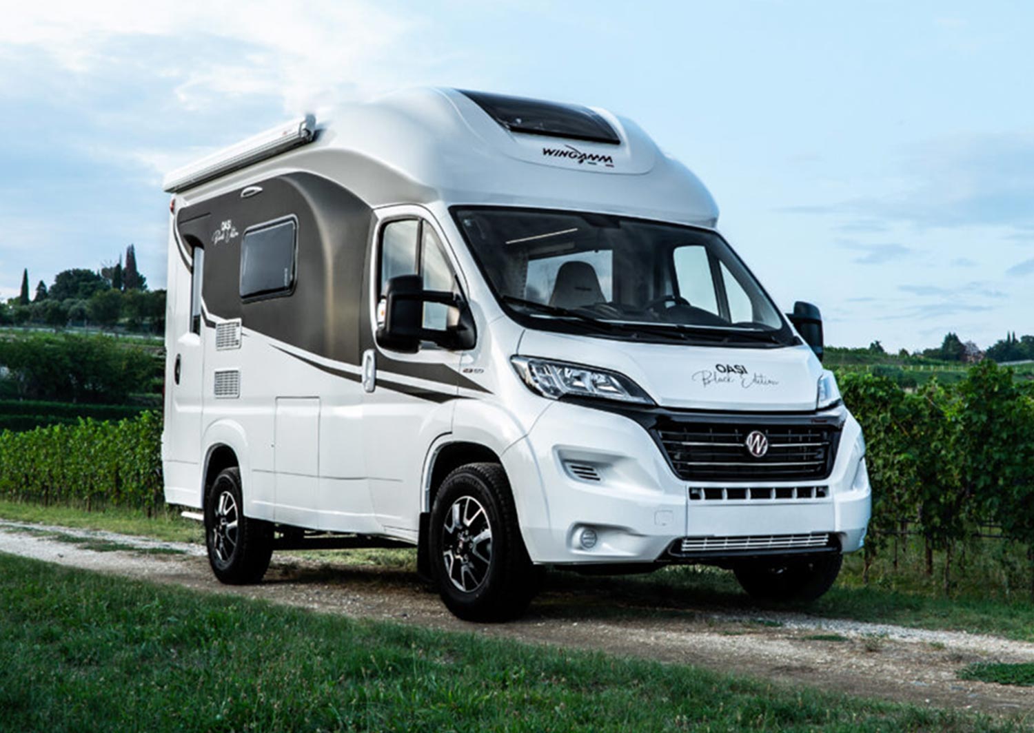 three quarter view of the Wingamm's Oasis 540.1 parked on a dirt road near a grove