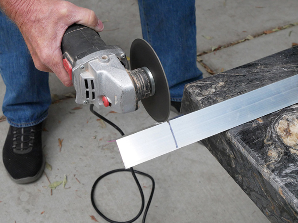 man cutting the aluminum angle stock into three brackets