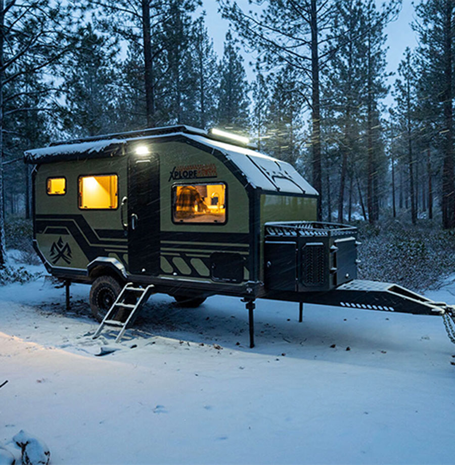 trailer parked in the woods while it's snowing