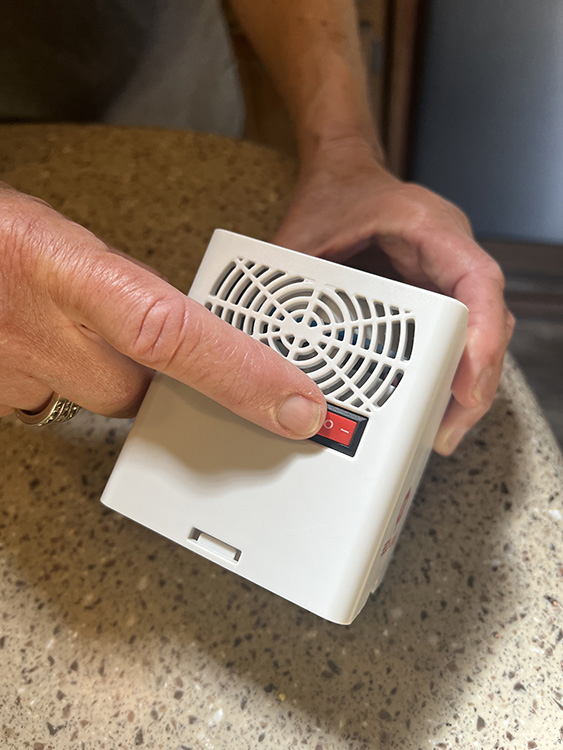 finger flipping red switch on white hand held fan