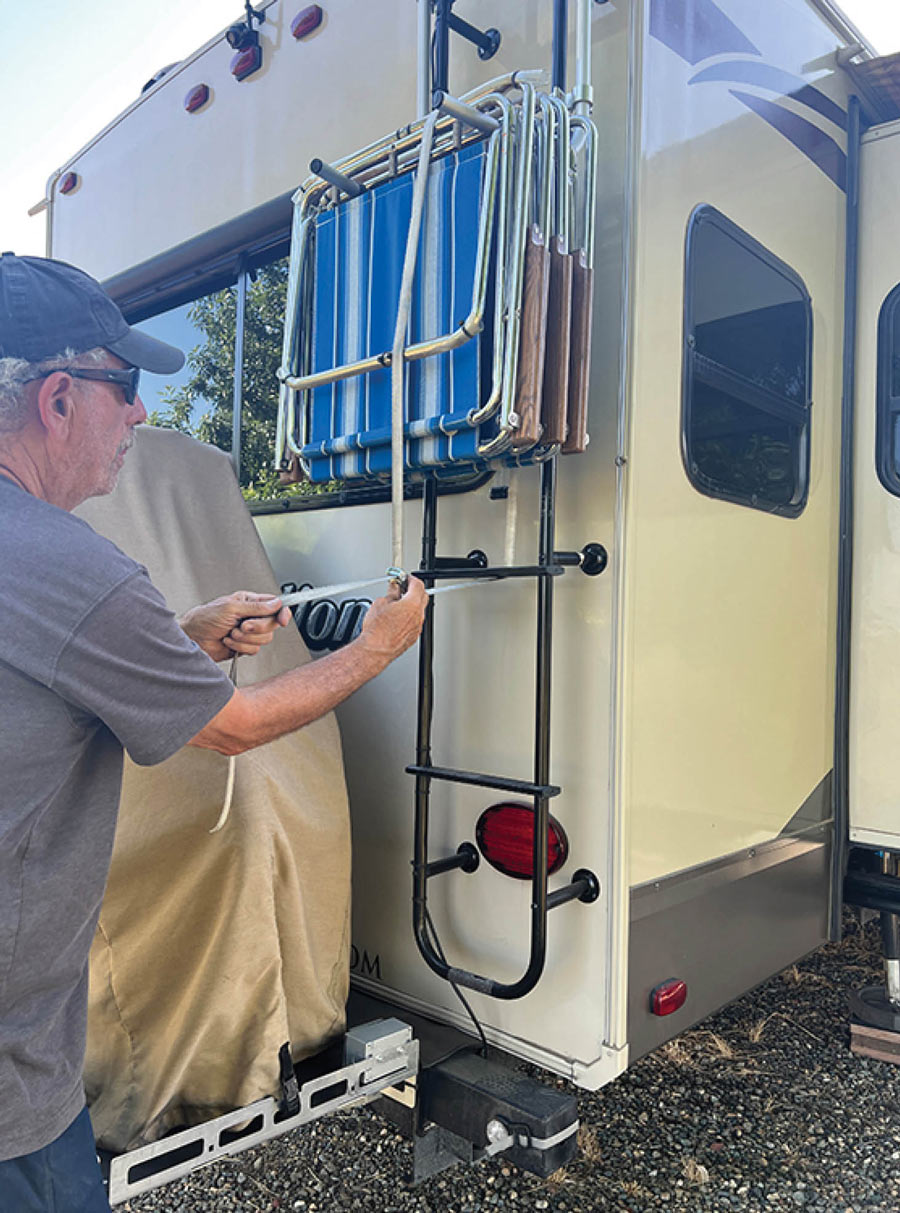 man hanging chairs on the back of an RV