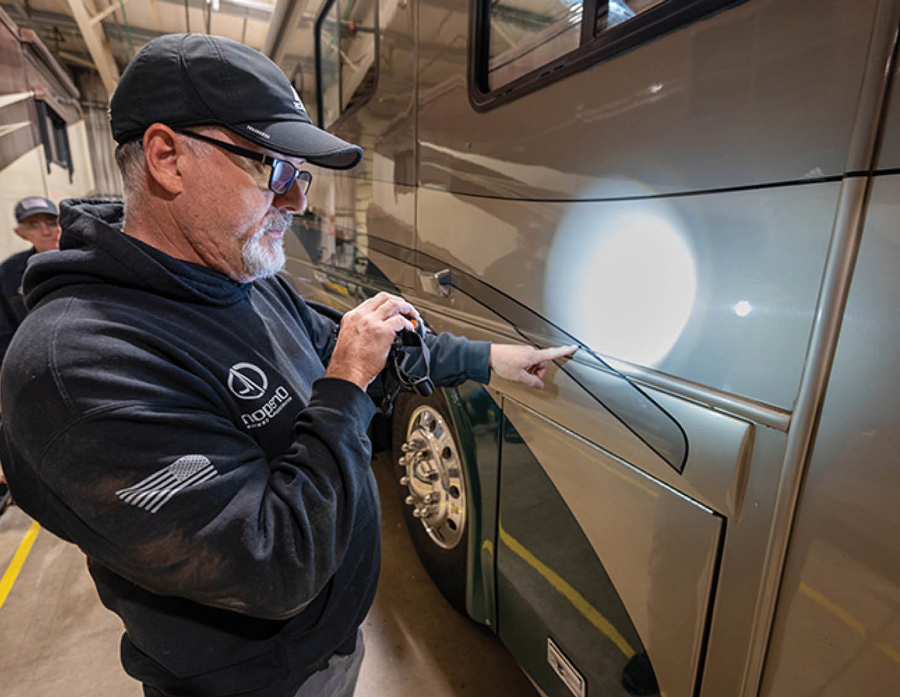 man using a flashlight to look closely at an RV