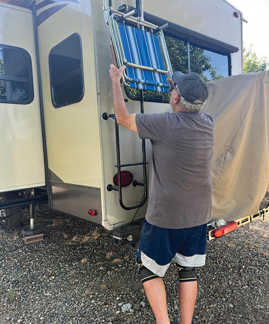 man hanging a chair on the back of an RV