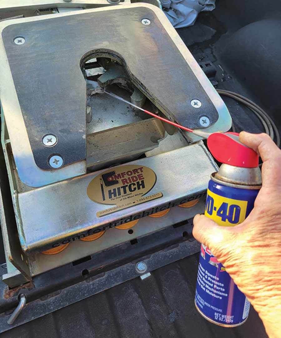 hand spraying WD-40 into a tow-link