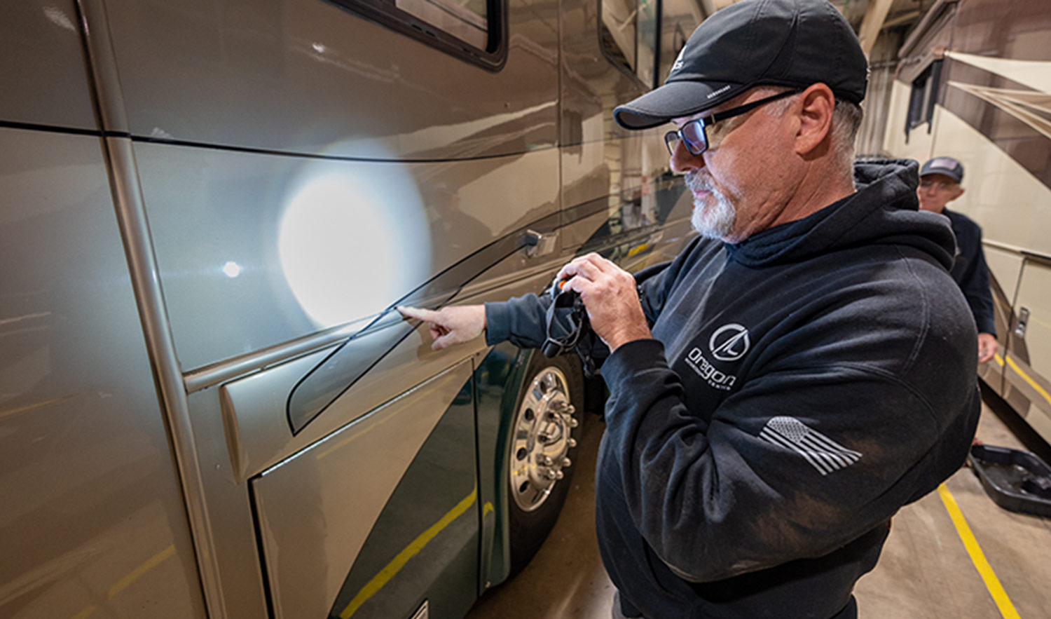 Matt Bryan, Oregon Motorcoach Center’s assistant service manager, stands by an RV with a flashlight doing an exterior inspection