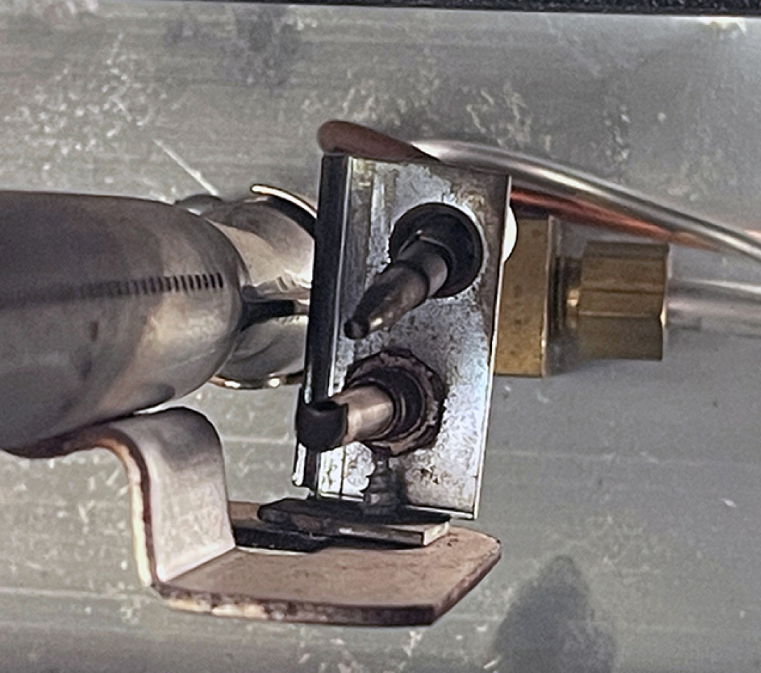 The oven pilot in the old Atwood is shown here. The pilot thermal bulb is covered with soot, and should be cleaned with emery paper. The main oven burner is to the left.