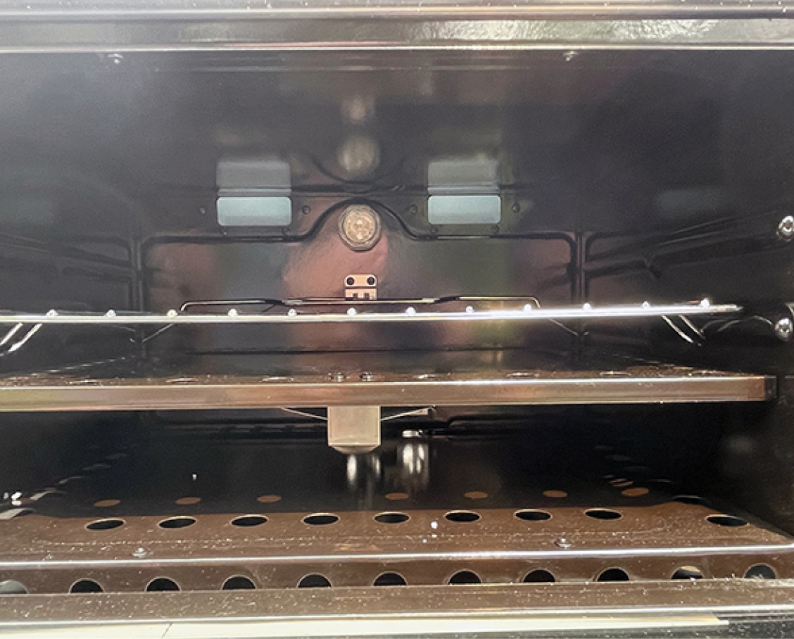 If you opt to use a pizza stone, it must not cover any of the vent holes on the burner shelf, as seen here.