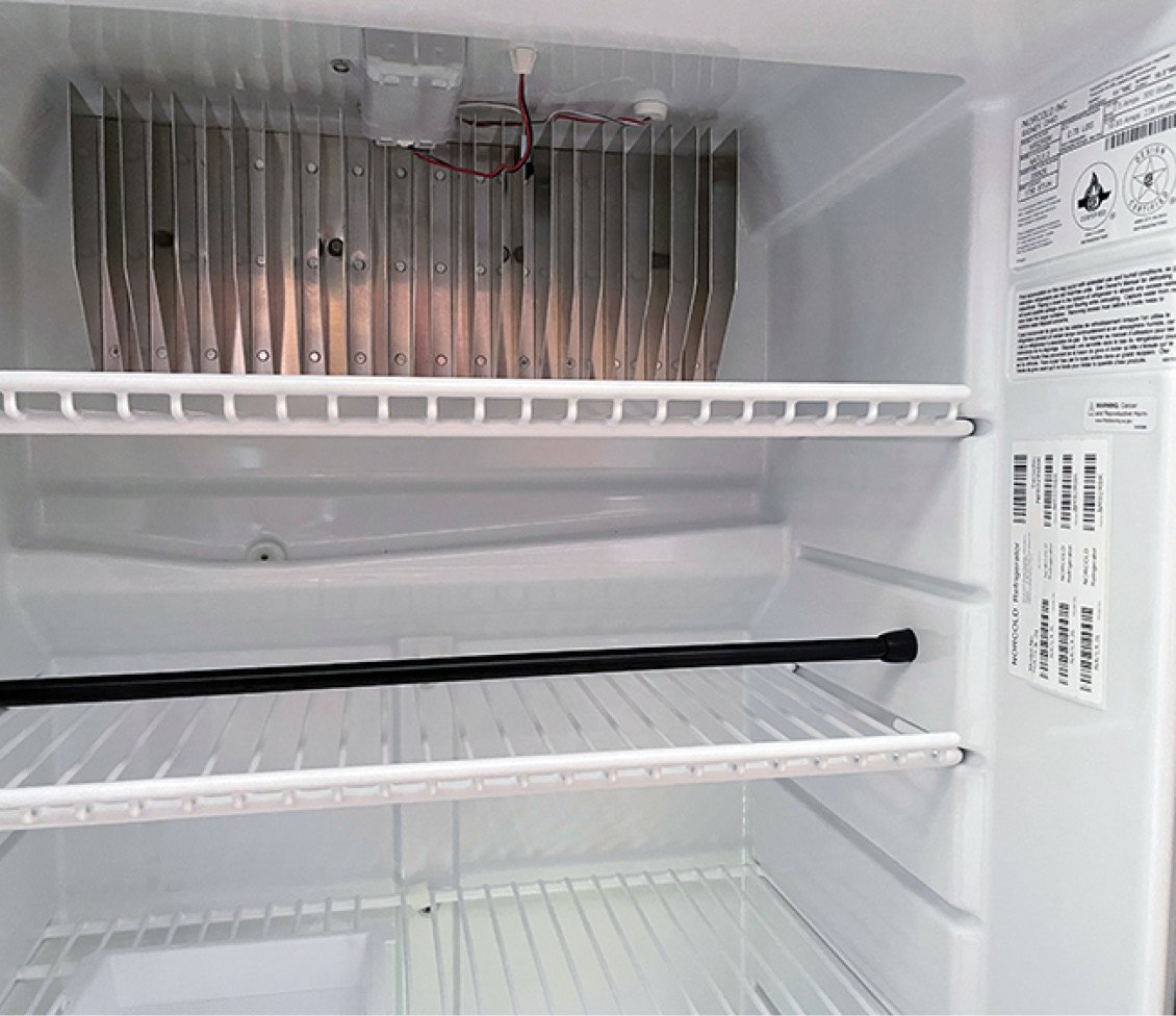 The inside of the fresh food compartment has the cooling fins on the upper rear. The thermistor, which reads the temperature in the refrigerator, is clipped to a fin in the middle on this model. If your unit isn’t staying cold, check that this is attached correctly. It can detach — which will upset the cooling capability of the refrigerator. Under the fins is a molded-in condensate catcher which drains to the small hose connection in the rear.