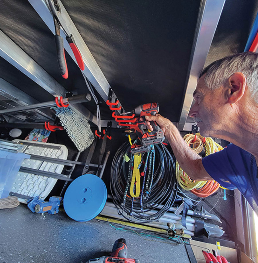 man drilling a rack in his RV storage