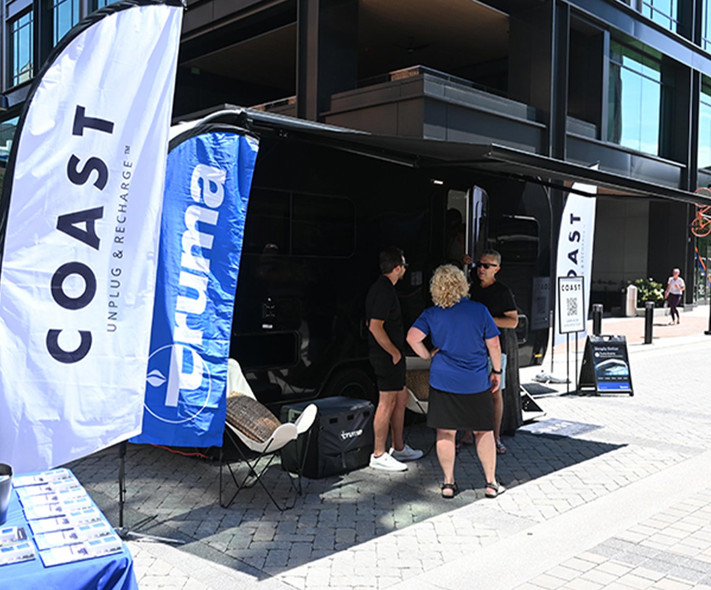 a Coast vendor stand with a representative talking to a man and a woman