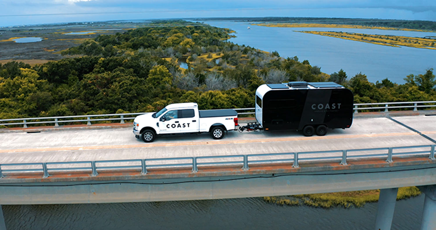 the Coast 1 trailer hitched to a heavy duty white truck traveling down an elevated highway