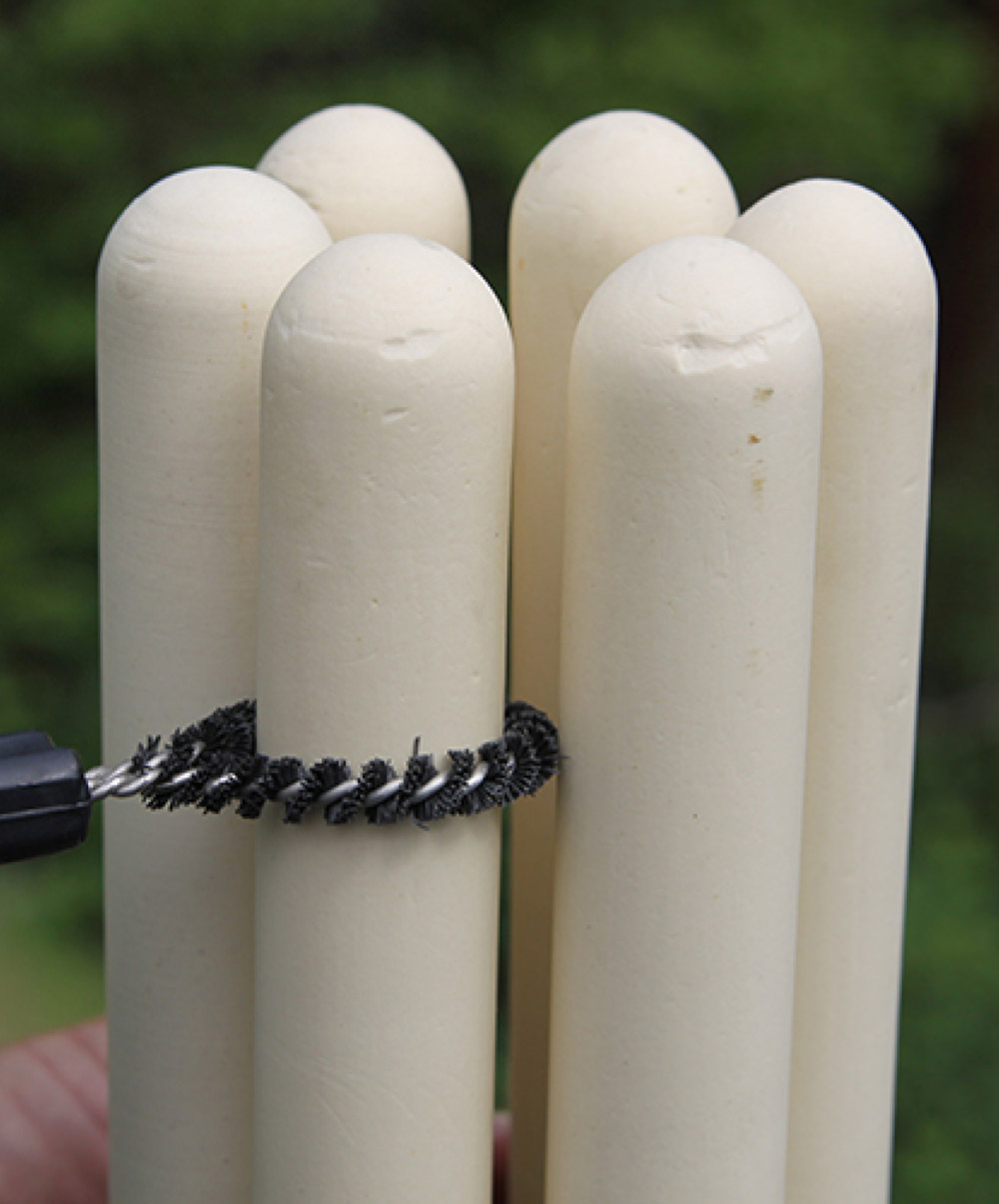 Ceramic candle filter being cleaned with specialized brush