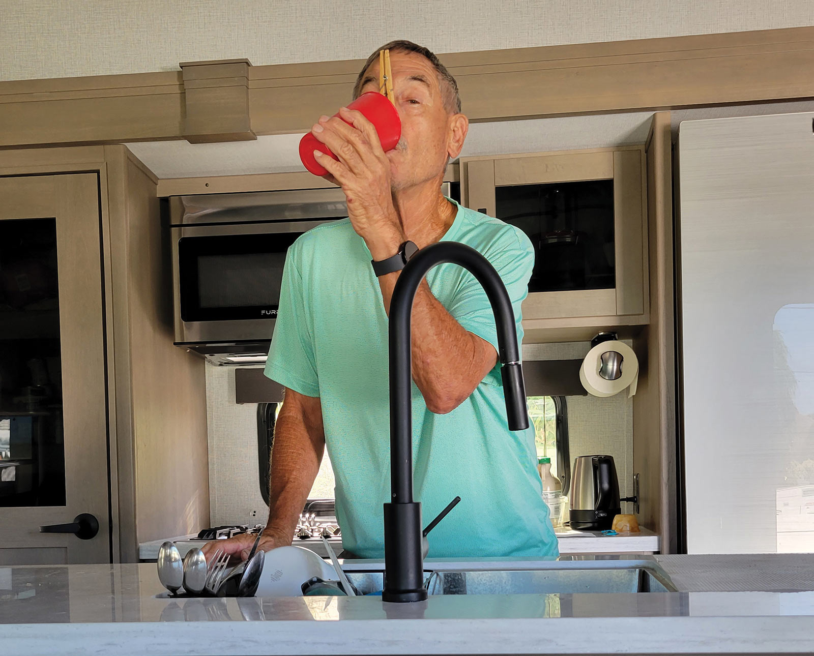 Man drinking cup of tap water with clothespin pinching his nose