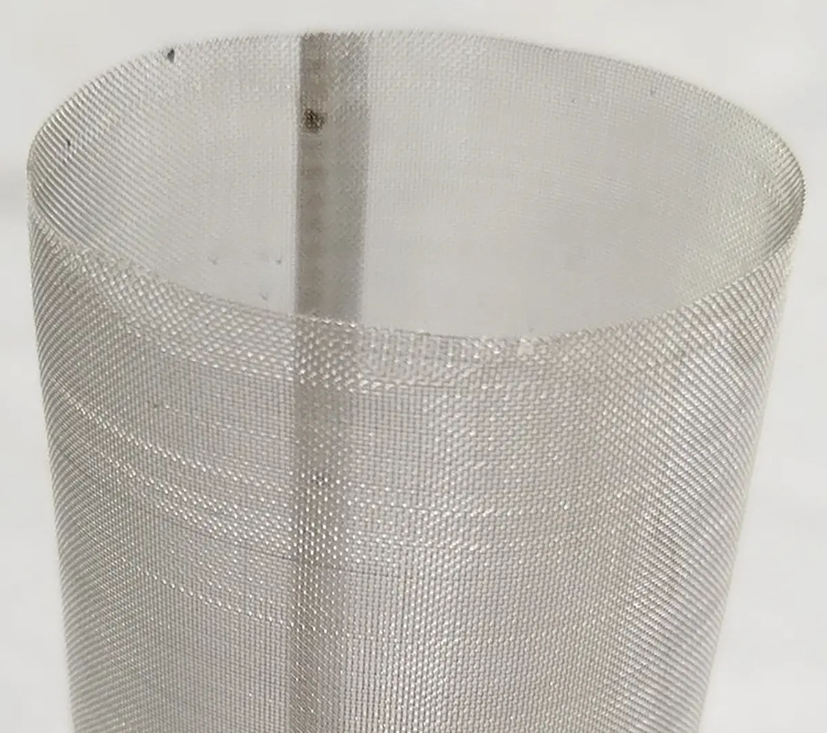 Close-up photograph perspective of a mesh filter; They are rated by the number of openings in one linear inch. The 100-mesh screen is the finer of the two provided with the garden hose attachment kit.