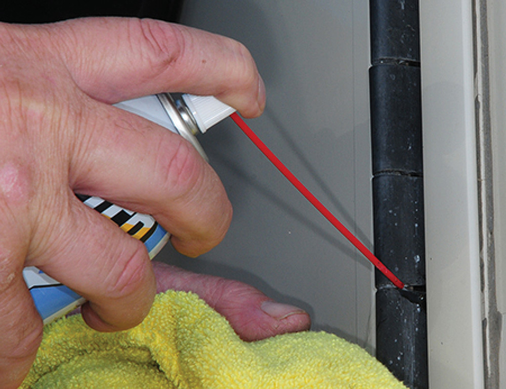 Spraying door hinge with Blaster Dry Lube