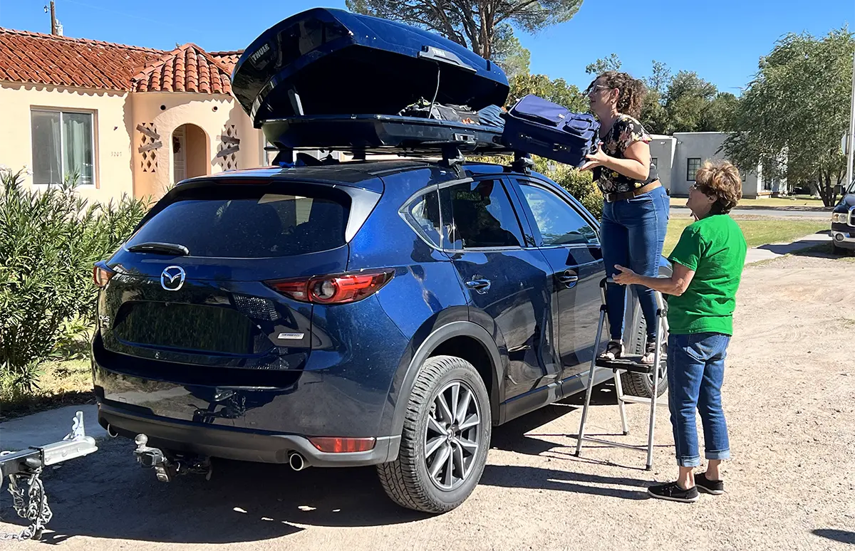 Two people packing roof box on a Mazda CX-5