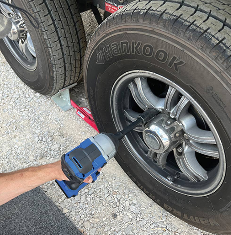 hand using a drill to remove bolts off a tire rim