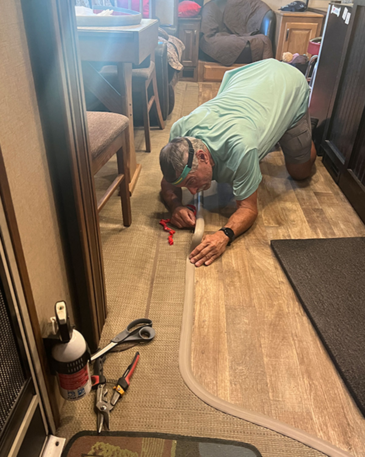 Man with head lamp on, bent over while laying the transitional strip down.