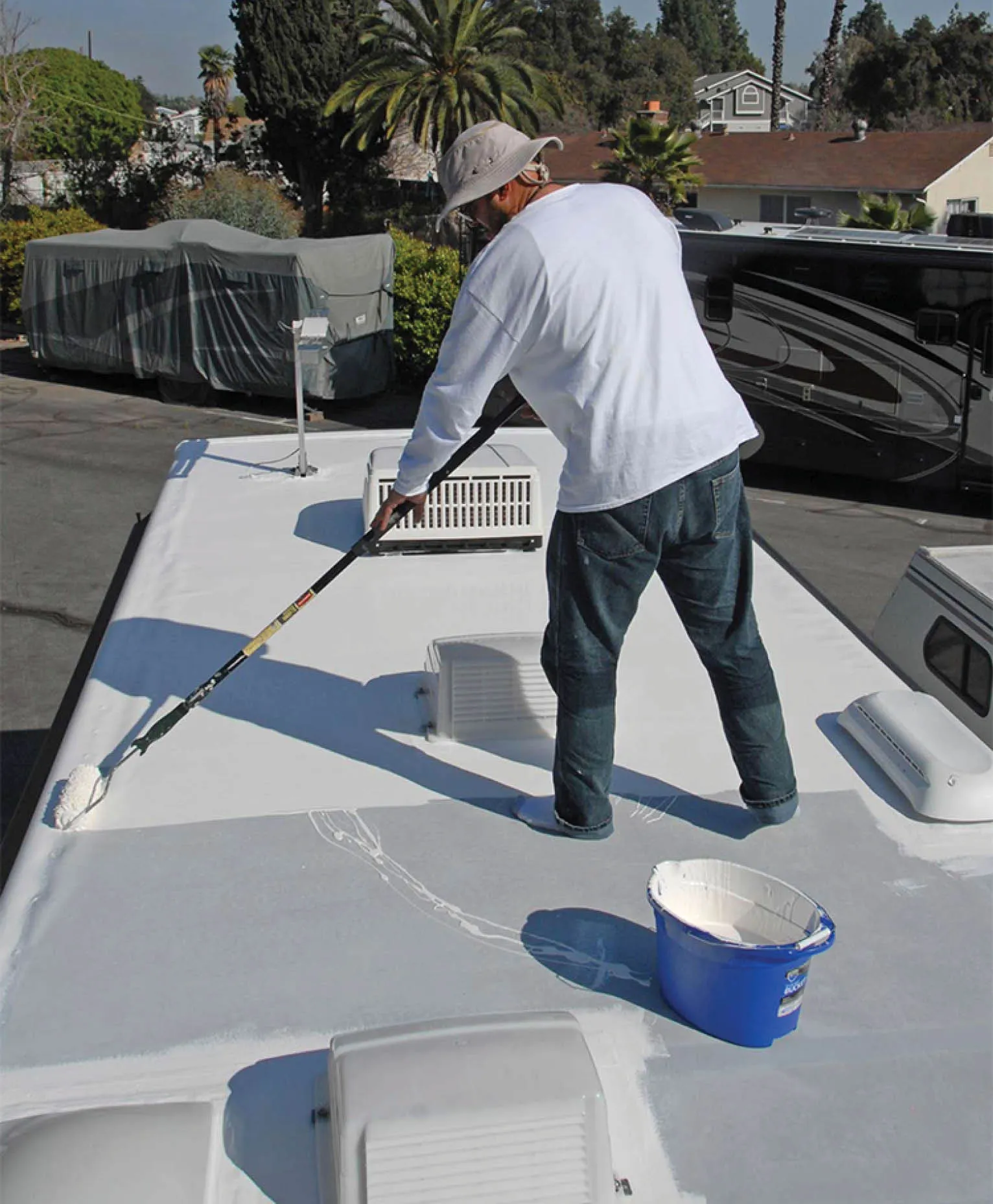 man painting a rubber roof white