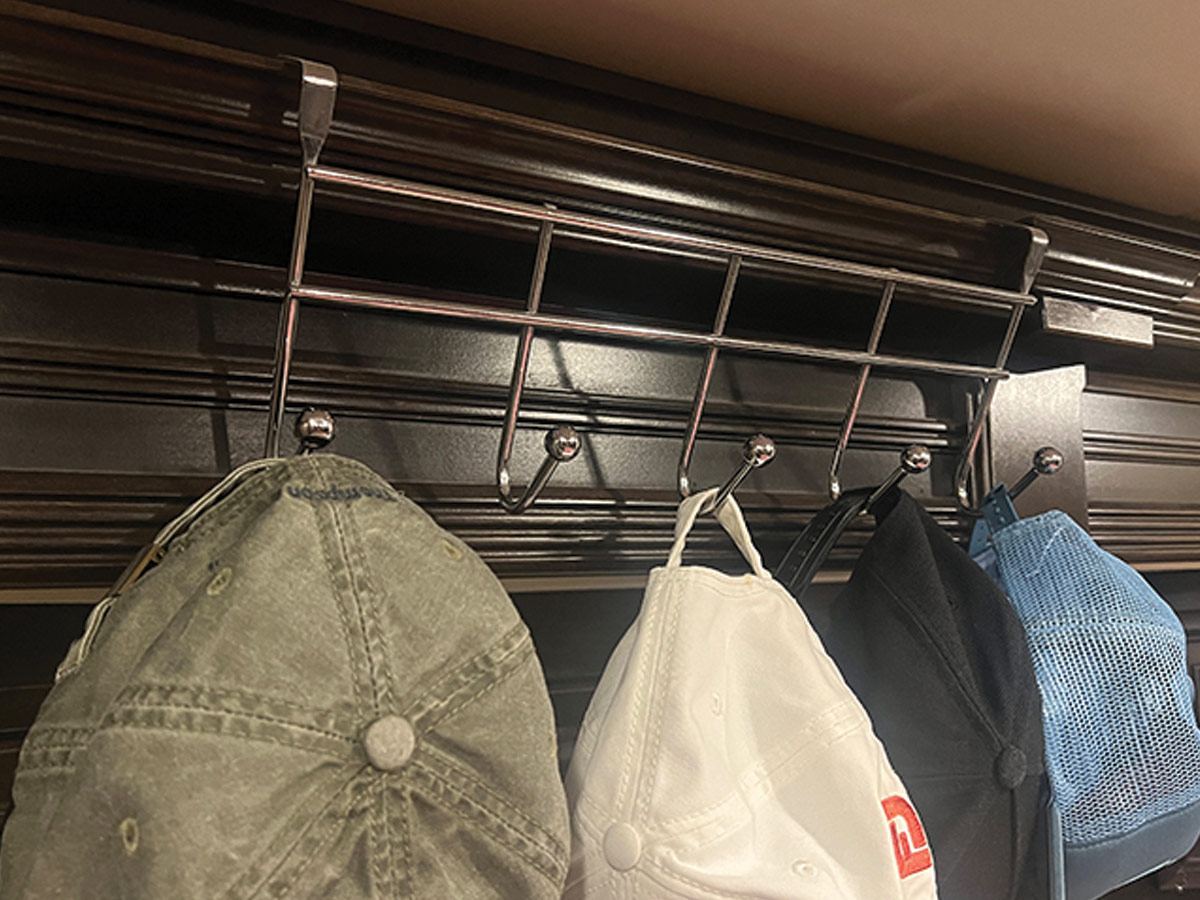 four hats hanging on metal hooks