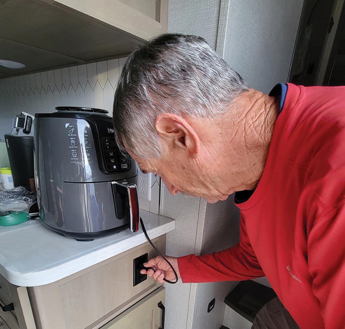 man plugging air fryer into outlet