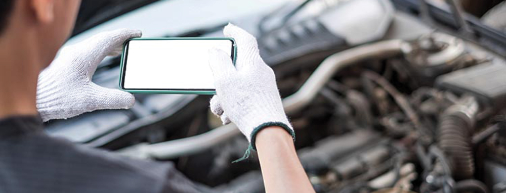 person using a phone to take a picture of an engine under a car hood